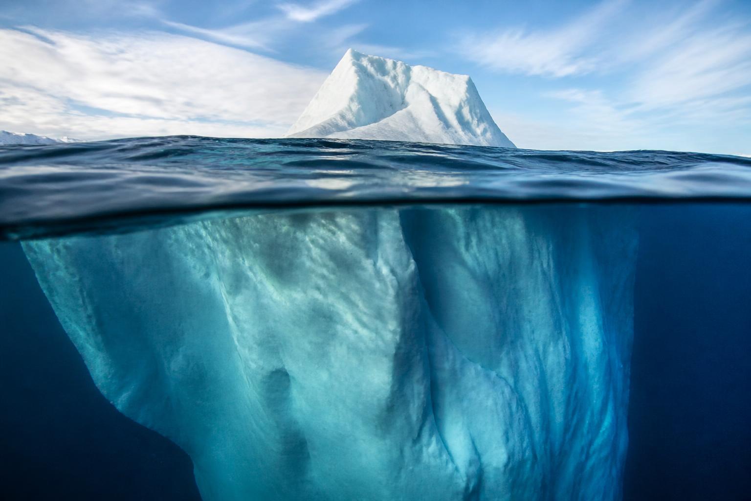 An iceberg with a small tip above the waterline and an enormous submerged mass below it